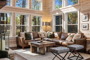 A cozy cabin interior with a leather sofa, a wooden coffee table, and a lamp. - NEW! Outdoor Lounge, Hot Tub, Firepit, King Suites (Broken Bow)