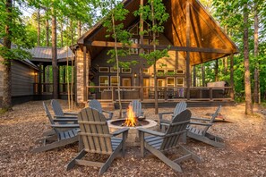 A cabin with a fire pit and Adirondack chairs in front. - NEW! Outdoor Lounge, Hot Tub, Firepit, King Suites (Broken Bow)