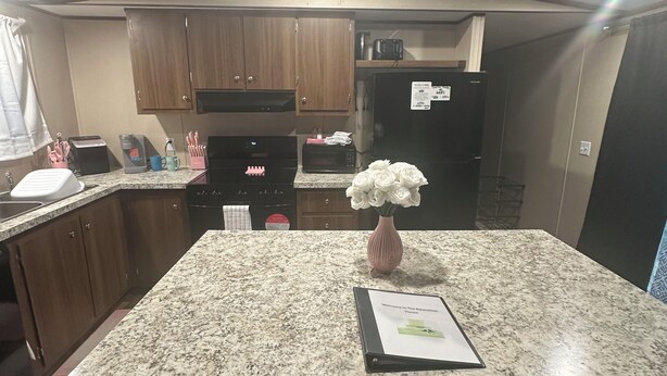 Una cucina compatta con mobili in legno, un forno a microonde, un tostapane e un frigorifero.