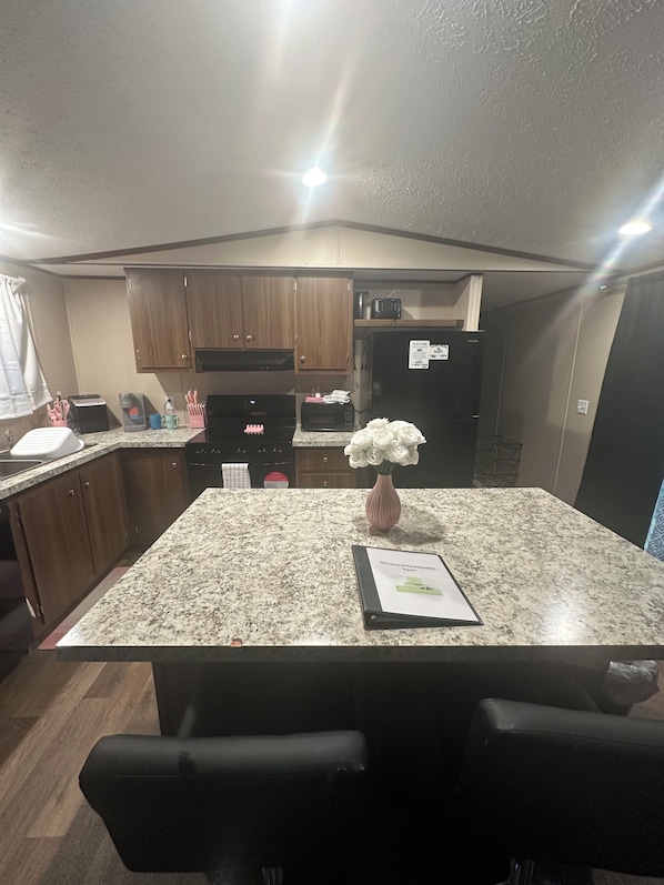 A compact kitchen with wooden cabinets, a microwave, a toaster, and a refrigerator.