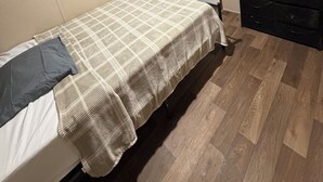 Una camera da letto con un letto, una televisione, una cassettiera e una porta.