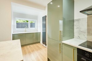 A modern kitchen with a window, a built-in stove, and a marble countertop.