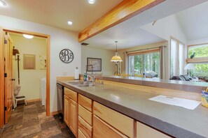A kitchen with a large island, wooden cabinets, a sink, and a window with a view of greenery. - 9 Quelah Condo- Community Pool, Community, BBQ & Fireplace (Bend)