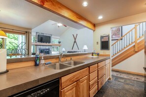A kitchen with wooden cabinets, a dishwasher, a double sink, and a wooden staircase. - 9 Quelah Condo- Community Pool, Community, BBQ & Fireplace (Bend)