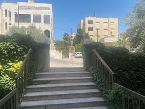 A staircase leading to a building with a clear view of the street and parked cars.