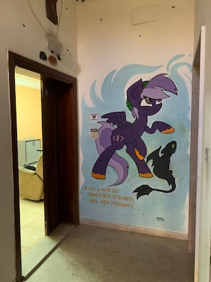 A hallway with a wall mural of a purple pony and a dragon, and a door leading to another room.
