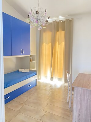 Una stanza con un letto a castello, un tavolo di legno, una sedia bianca e un lampadario.