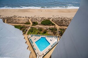 A pool with a view of the beach, surrounded by lounge chairs and a fenced area. - Oceanfront 1 Bed/1.5Bath-OutdoorPool-WiFi-Laundry (Ocean City)