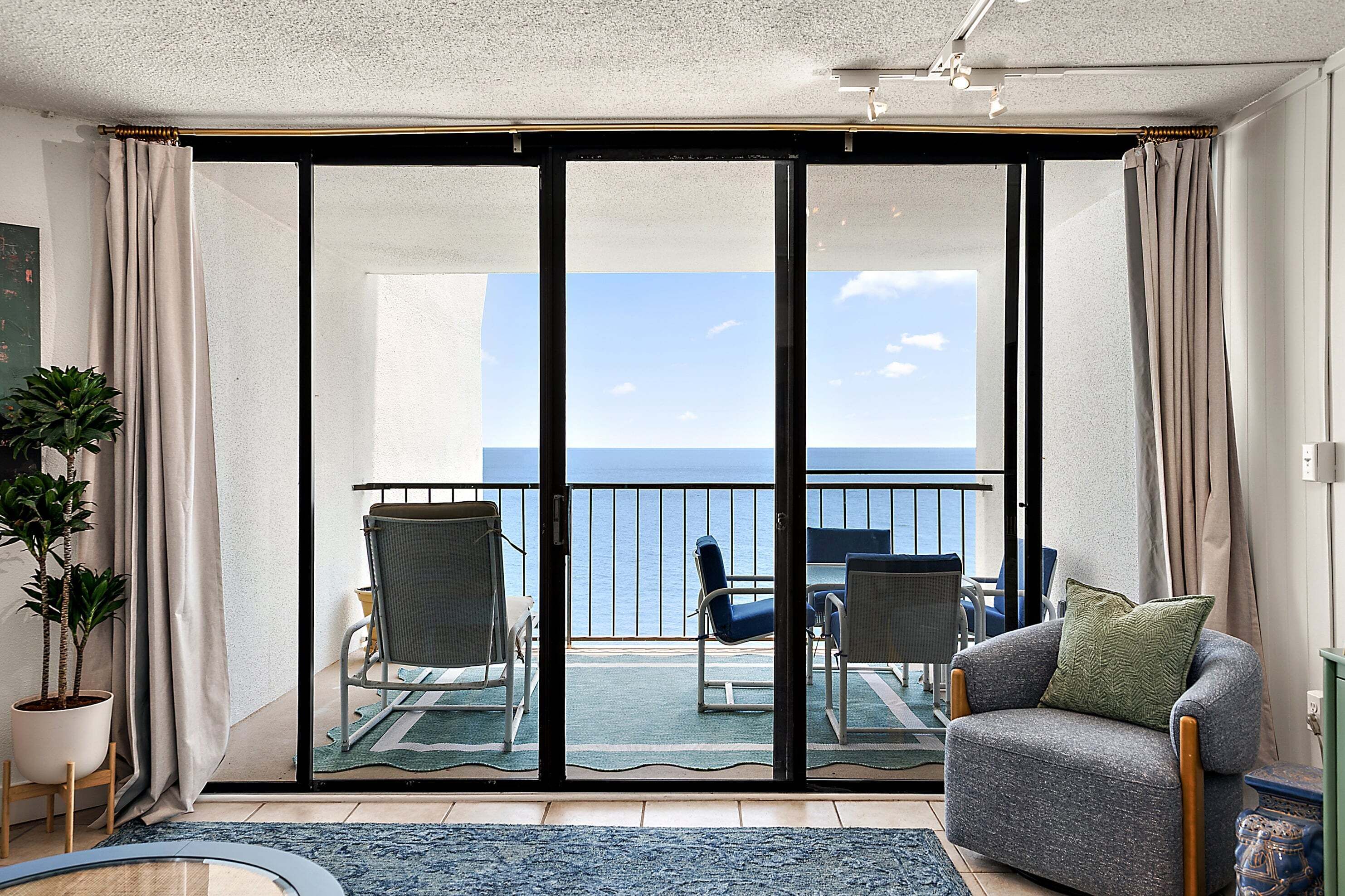 Ein Balkon mit Meerblick, einer Couch und zwei Stühlen.
