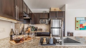 Une cuisine moderne avec des meubles en bois foncé, des appareils en acier inoxydable, un plan de travail en granit et une machine à café.