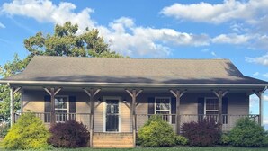 A two-story house with a front porch, a well-maintained lawn, and mature trees in the background.