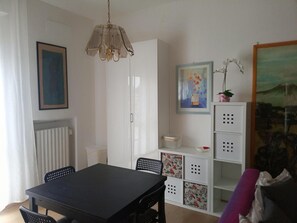 A dining area with a table and chairs, a radiator, a white cabinet with storage drawers, and a hanging light fixture.