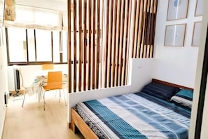 Ein Schlafzimmer mit einem Bett, einem Sessel, einem Schreibtisch und einem Fenster.