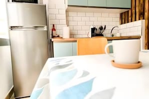 Eine Küche mit einem Kühlschrank, einer Spüle und einem Tisch mit einer Tasse.