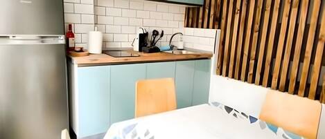 A compact kitchen with a refrigerator, a sink, and a wooden countertop.