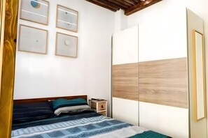 Een slaapkamer met een bed, een kledingkast en aan de muur bevestigde fotolijstjes.
