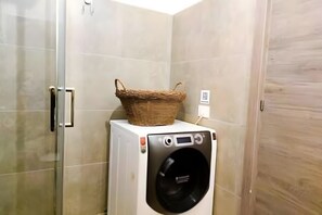 Ein kleiner Waschbereich mit Waschmaschine und Wäschekorb.