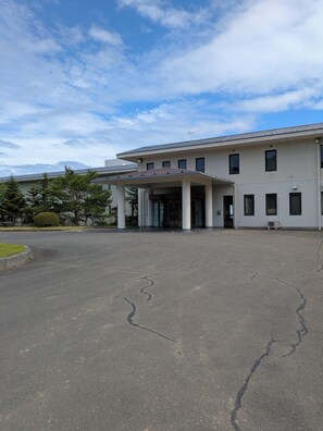 A modern building with a covered entrance and a parking lot. - jiros garden (Isinomaki)