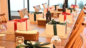 A dining table set with neatly arranged gift boxes, a bottle of wine, and a glass. - jiros garden (Isinomaki)