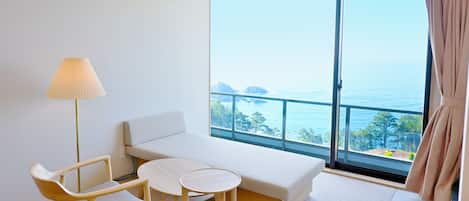 Una habitación con un ventanal grande, un sofá, una mesita y una silla.