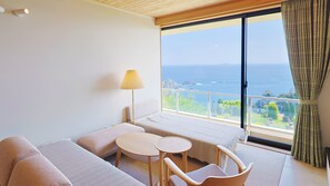 A hotel room with a bed, a small table, a chair, a lamp, and a view of the sea. - jiros garden (Isinomaki)