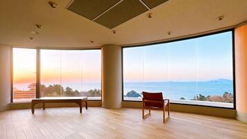 A spacious room with large windows offering a view of the sea and distant land.