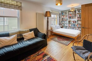 Une chambre à coucher avec un lit, un canapé, une bibliothèque, une lampe et une fenêtre.