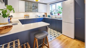 Una cocina moderna con una isla central, taburetes de bar y un refrigerador.
