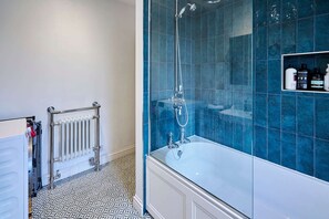 Une salle de bain avec une baignoire, une douche et des murs carrelés.