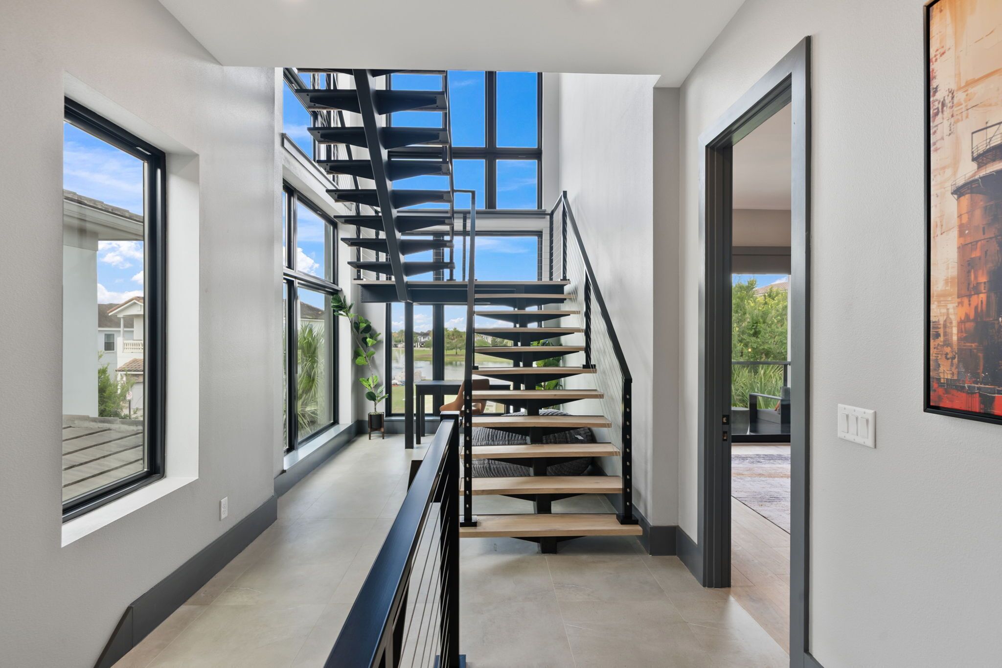 Un intérieur moderne avec un escalier en colimaçon, de grandes fenêtres et une vue sur l’extérieur.