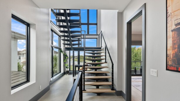 A modern interior with a spiral staircase, large windows, and a view of the outdoors. - WOW Home with Arcade Floor + Theater | Private Pool & Spa (Kissimmee)