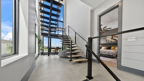 A modern interior with a staircase, a bed, and a view through a window. - WOW Home with Arcade Floor + Theater | Private Pool & Spa (Kissimmee)