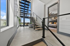 Ein modernes Interieur mit Treppe, Bett und Blick durch ein Fenster.