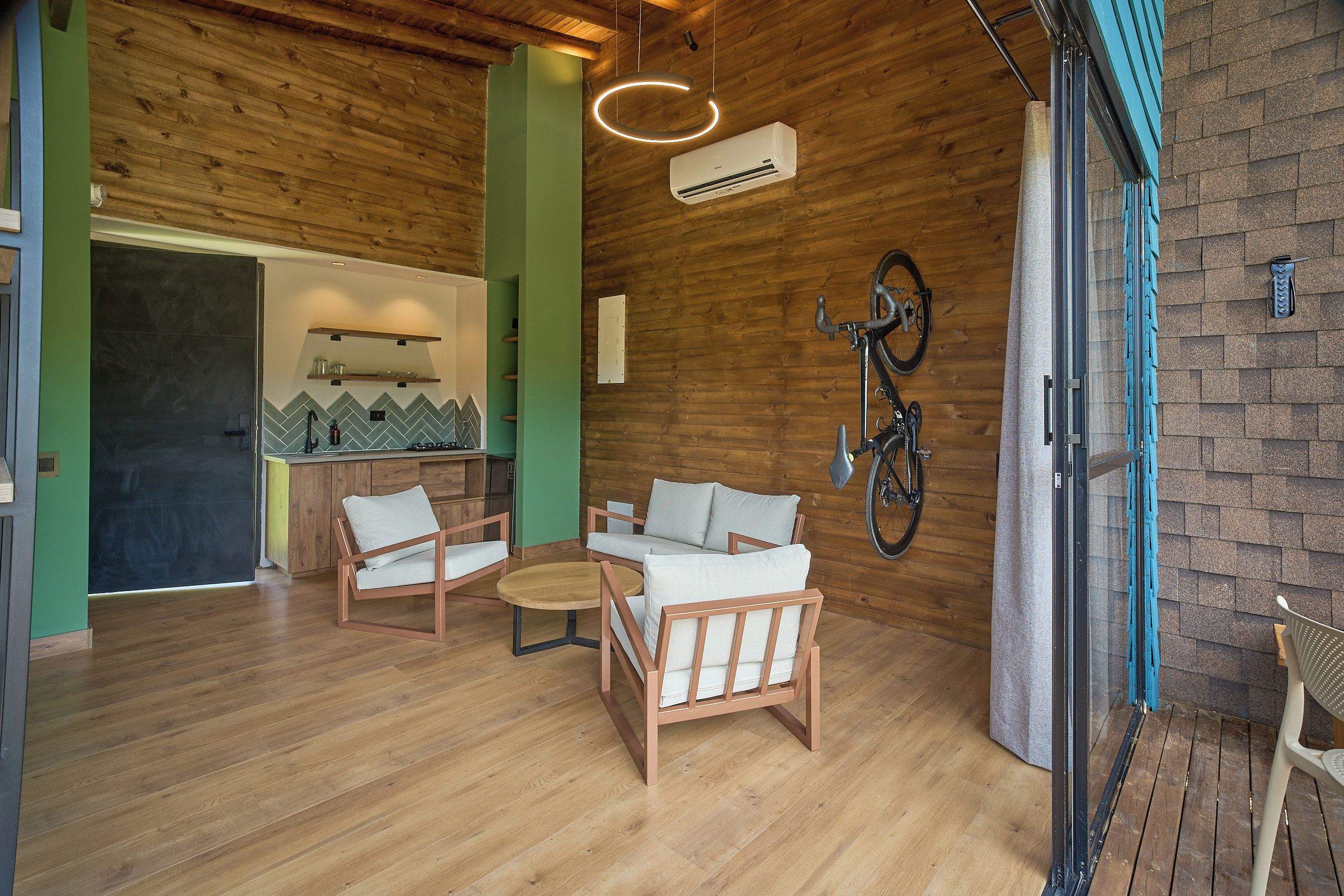 A modern interior with wooden flooring, a sofa set, a round coffee table, and a bicycle mounted on the wall.