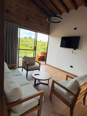 A modern living room with a sofa, chairs, a coffee table, and a TV mounted on the wall.