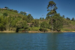 A lakeside property with a house on a hill, surrounded by trees and vegetation. - Lagoa by Loop (Peñol)