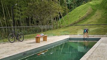 Una piscina con un banco de madera y una bicicleta.