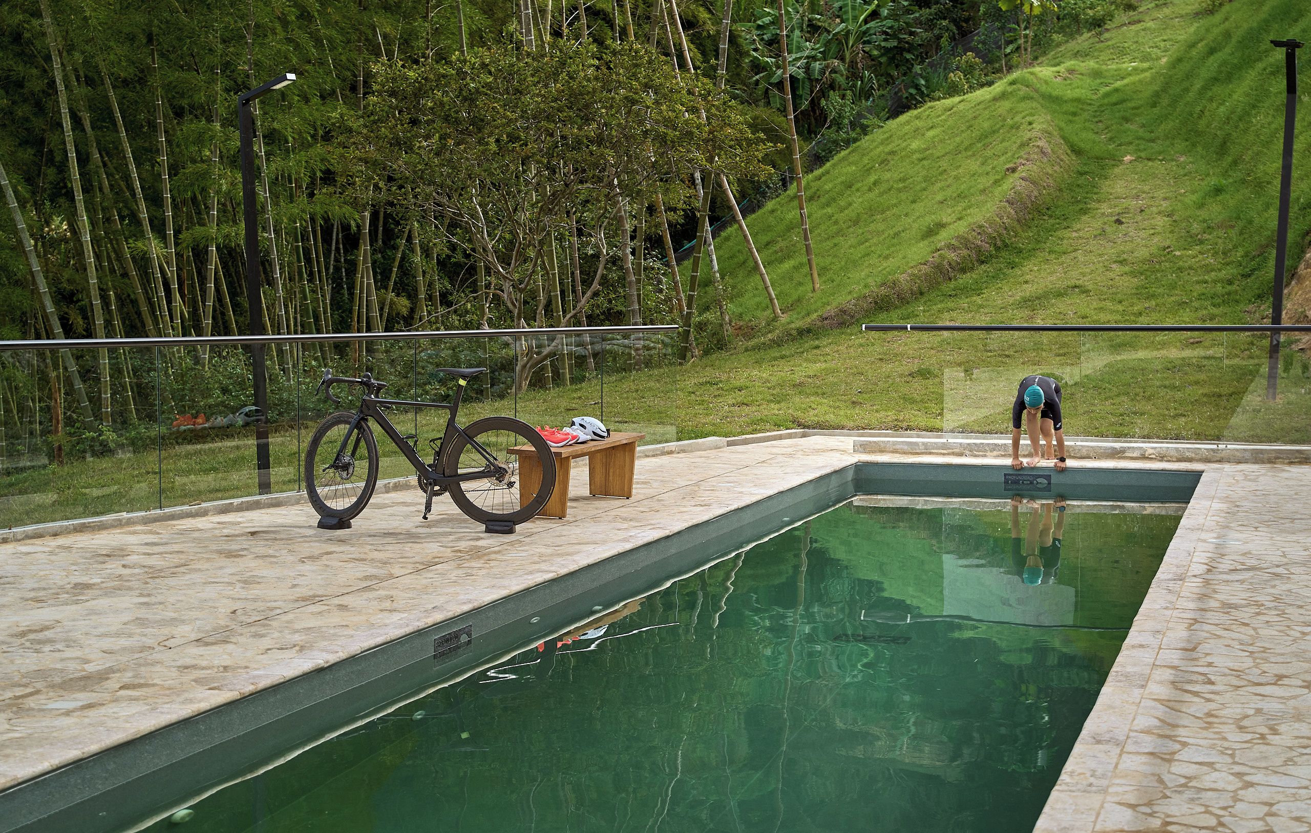 Una piscina con una bicicleta estacionada cerca, rodeada de vegetación.