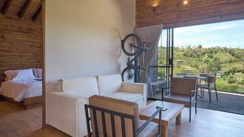 A modern room with a wooden ceiling, a sofa, a bicycle, and a view of a green landscape.