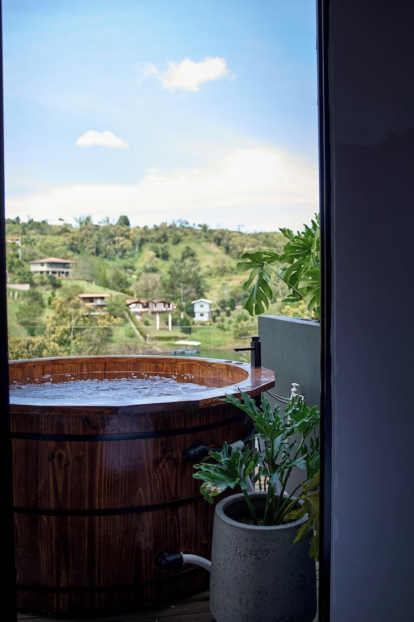Una bañera de madera con vistas a un paisaje montañoso y casas a la distancia.