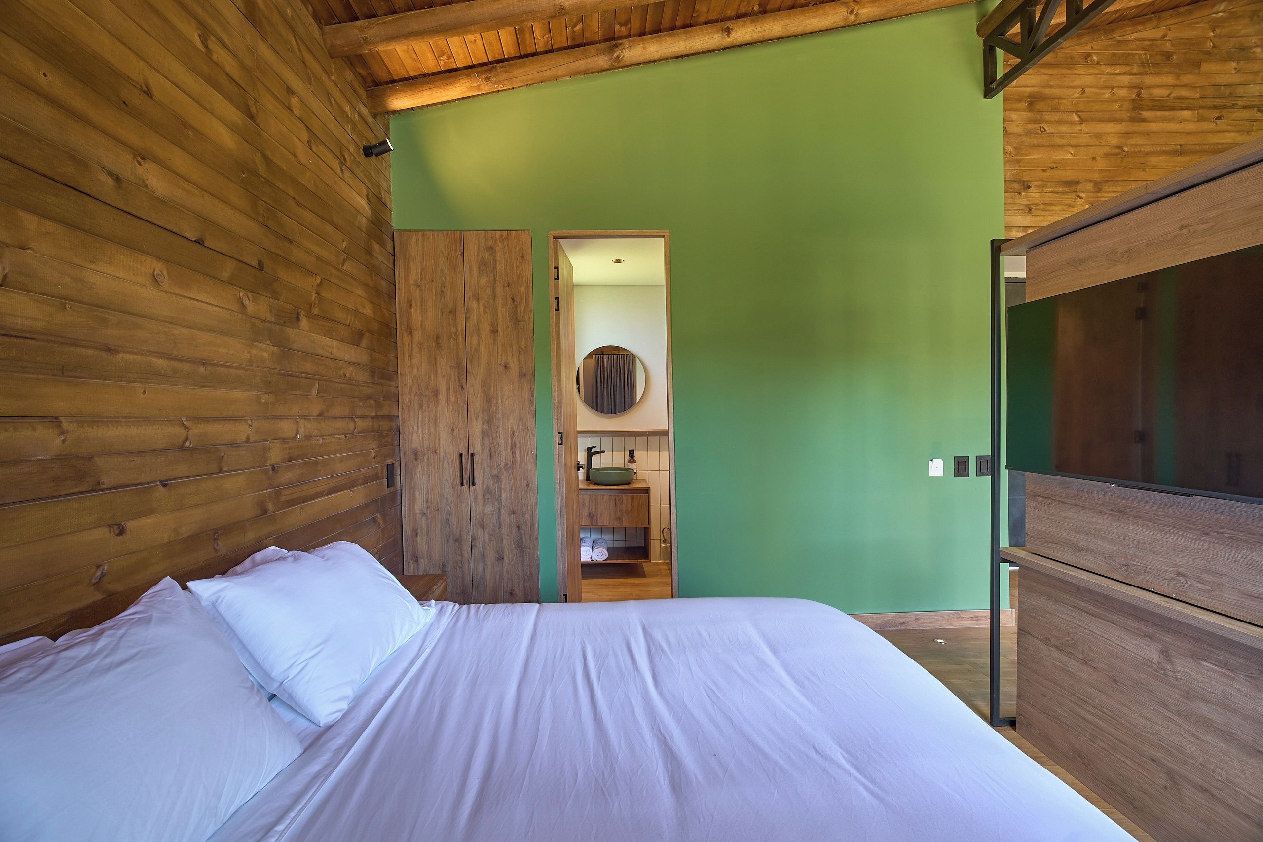 Un dormitorio con una cama de madera, una pared verde y un armario de madera.