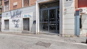 En bygning med en stor garageport, graffiti på væggen og et brønddæksel i jorden.