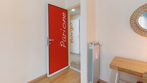 En gang med en rød dør med påskriften 'Parione' og en hvid dør med påskriften 'Borgo'.