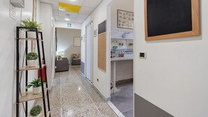 Ein Korridor mit einer Pflanzenwand, einer Kreidetafel und einem Schwarzesbrett mit verschiedenen Gegenständen.