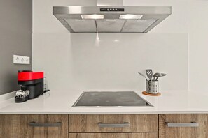 A kitchen with a built-in stovetop, a coffee maker, and a utensil holder.