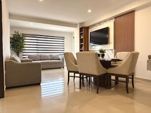 A modern living room with a sofa, chairs, a TV, and a plant. - Moderno Departamento en Torre 5 by GPS (Mazatlán)