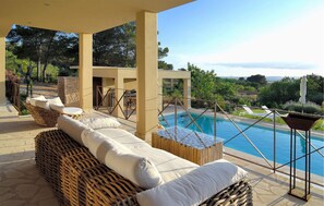 Ein Poolbereich mit Korbmöbeln und einer Glasbrüstung mit Blick auf den Pool.