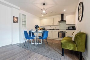 A modern kitchen with white cabinets, a black range hood, and a microwave.