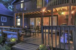 A wooden deck with outdoor seating, a covered patio area, and a view of a cabin.