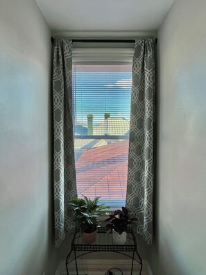 Ein Eckzimmer mit Fenster, einem Blumentopf und einem Metalltisch.